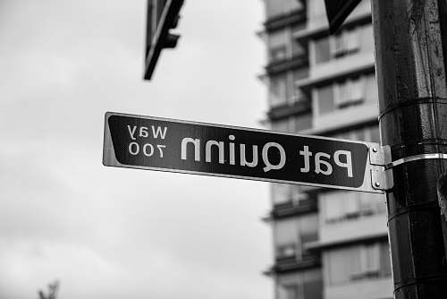 road sign grayscale photography of Pat Quinn signage street sign